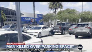 Parking lot with several vehicles, including a white sedan that appears to have been involved in an incident, as indicated by the